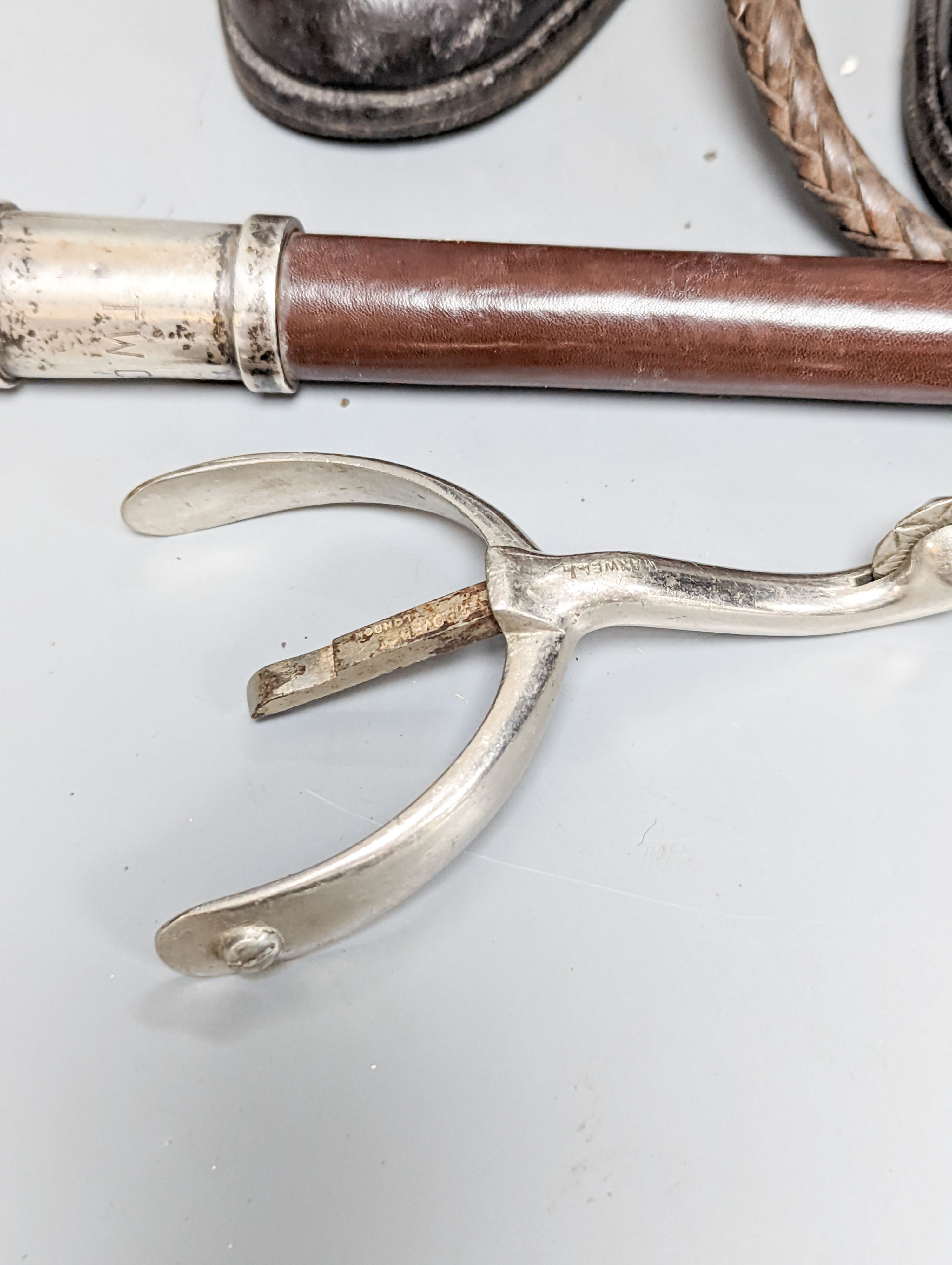 A pair of black leather riding boots with trees, a silver mounted whip and spurs